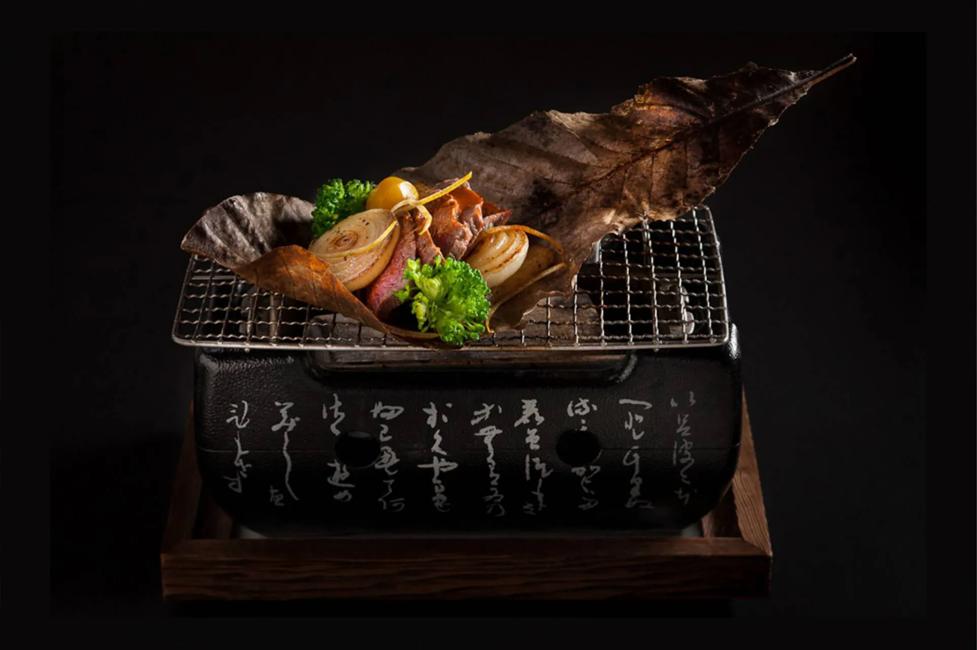 Grilled meat with onions and veggies on traditional Japanese grill.